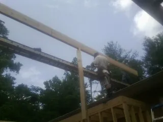 Carpenter setting a ridge beam over a new addition frame — Ice Dam Removal by Roofing Brothers in Luke