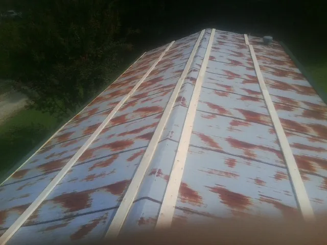 Rusted metal roof panels with new wood purlins before replacement — Storm Damage Roof Repair in Luke by Roofing Brothers