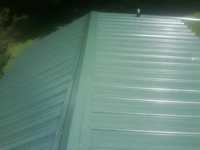 New green metal panels meeting at the ridge of a roof — Flat Roof Repair work by our crew in Luke