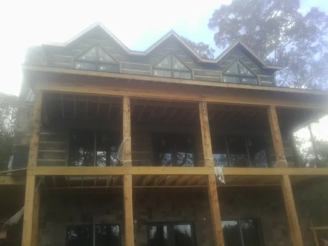 Dormers and porch framing on a large log home under construction — Roof Coating work by our crew in Luke