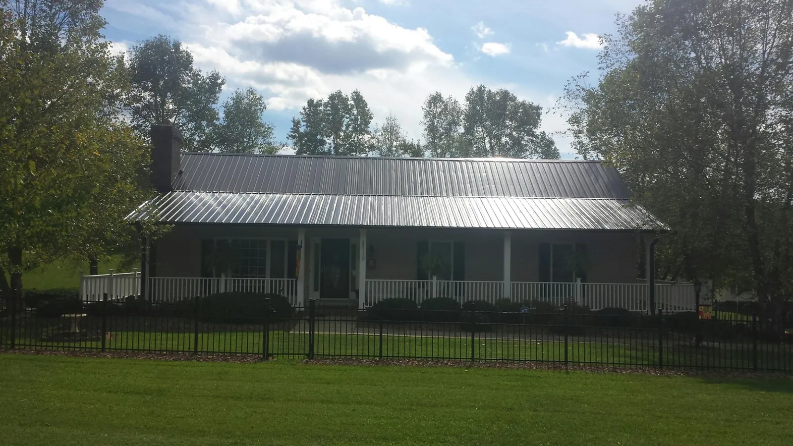 Gray metal roof on a brick ranch with a full width front porch — Gutter Guard Installation work by our crew in Luke