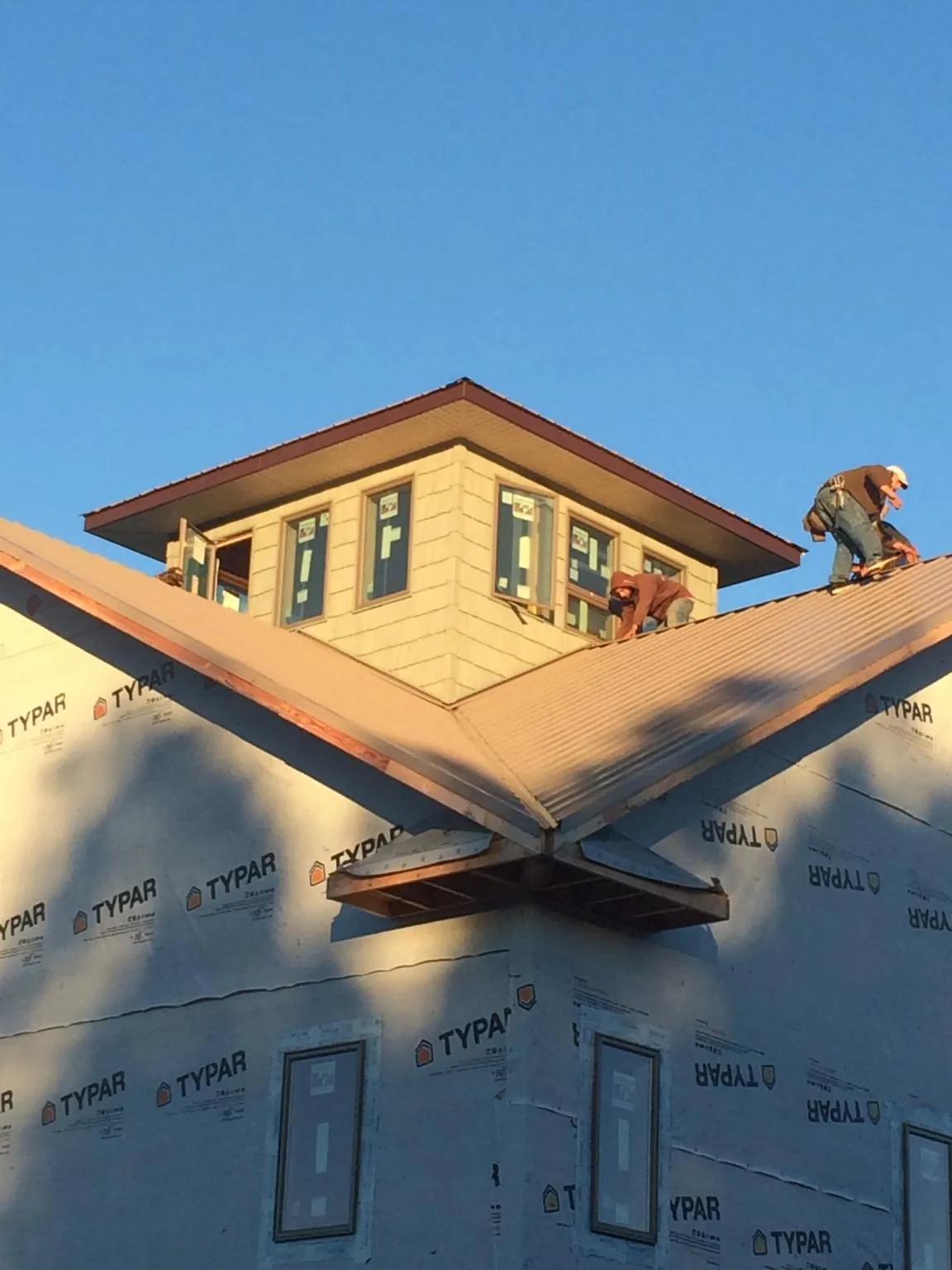 Roofers working around a rooftop cupola on a new metal roof at sunset — Roof Waterproofing in Luke by Roofing Brothers
